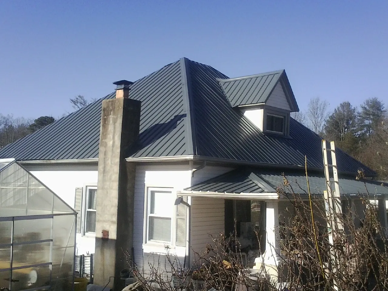 Dark blue standing seam metal roof on a white farmhouse with dormer in Swampscott