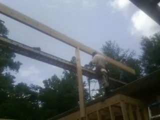 Carpenter setting a ridge beam over a new addition frame — Ice Dam Removal by Roofing Brothers in Swampscott