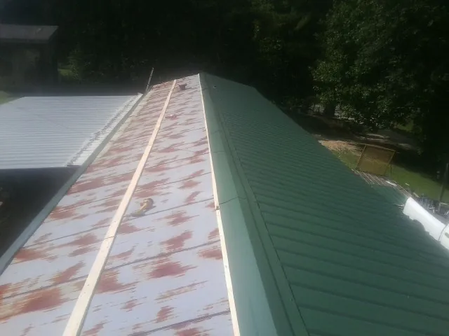 Old rusted panels beside newly installed green metal roofing — Wind Damage Roof Repair by Roofing Brothers in Swampscott