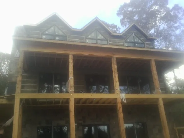 Dormers and porch framing on a large log home under construction — Roof Coating work by our crew in Swampscott