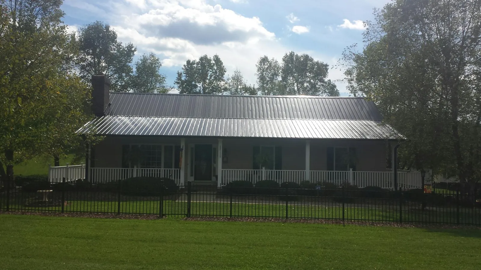 Gray metal roof on a brick ranch with a full width front porch — Gutter Guard Installation work by our crew in Swampscott