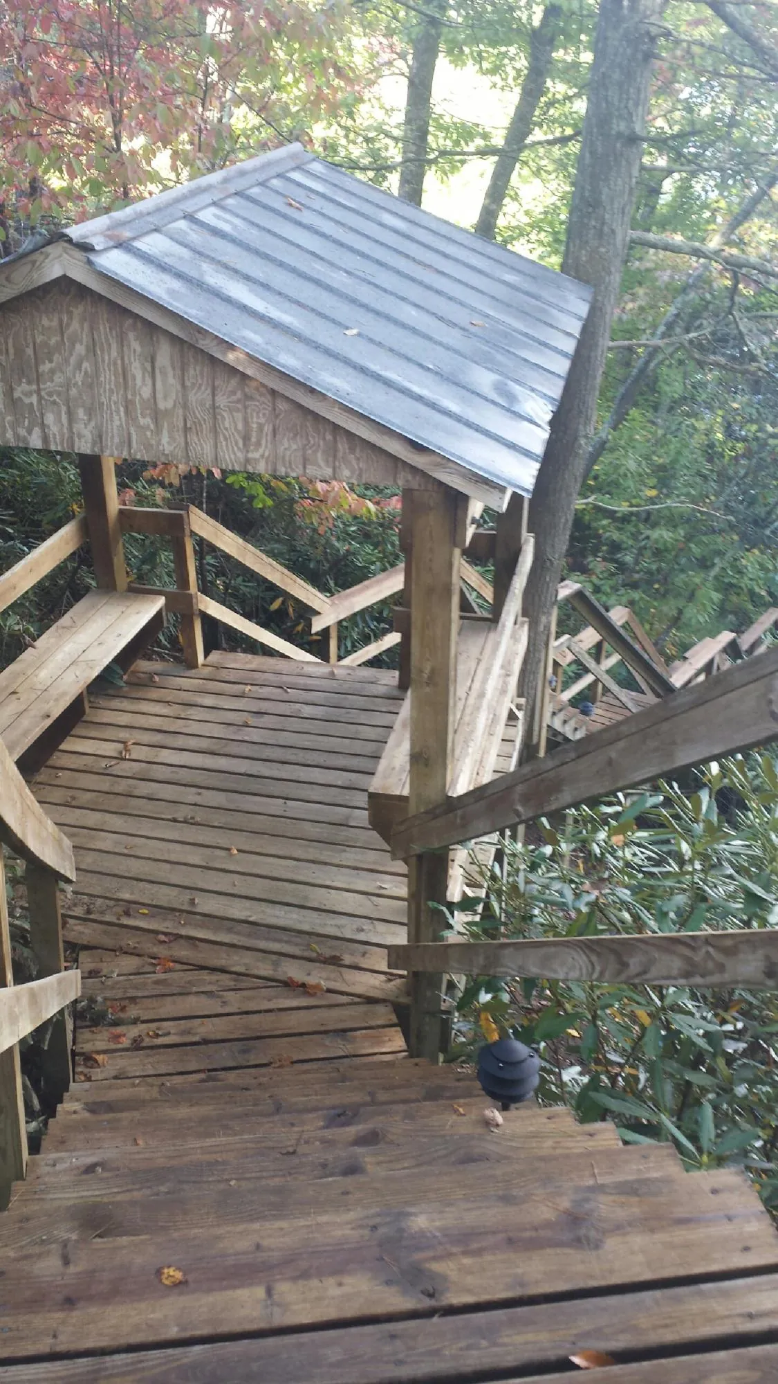 Metal roofed shelter over wooden steps on a wooded walkway — Skylight Repair & Installation work by our crew in Swampscott